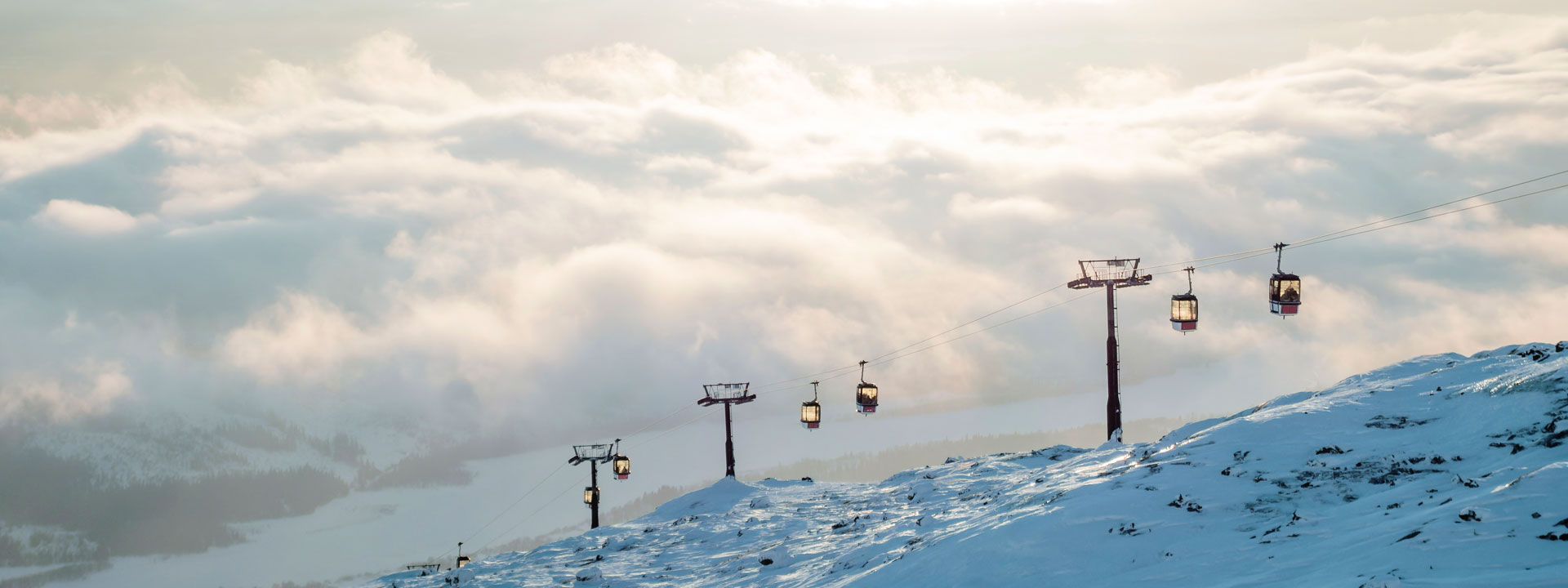 Ski lift with mountains and clouds in the background