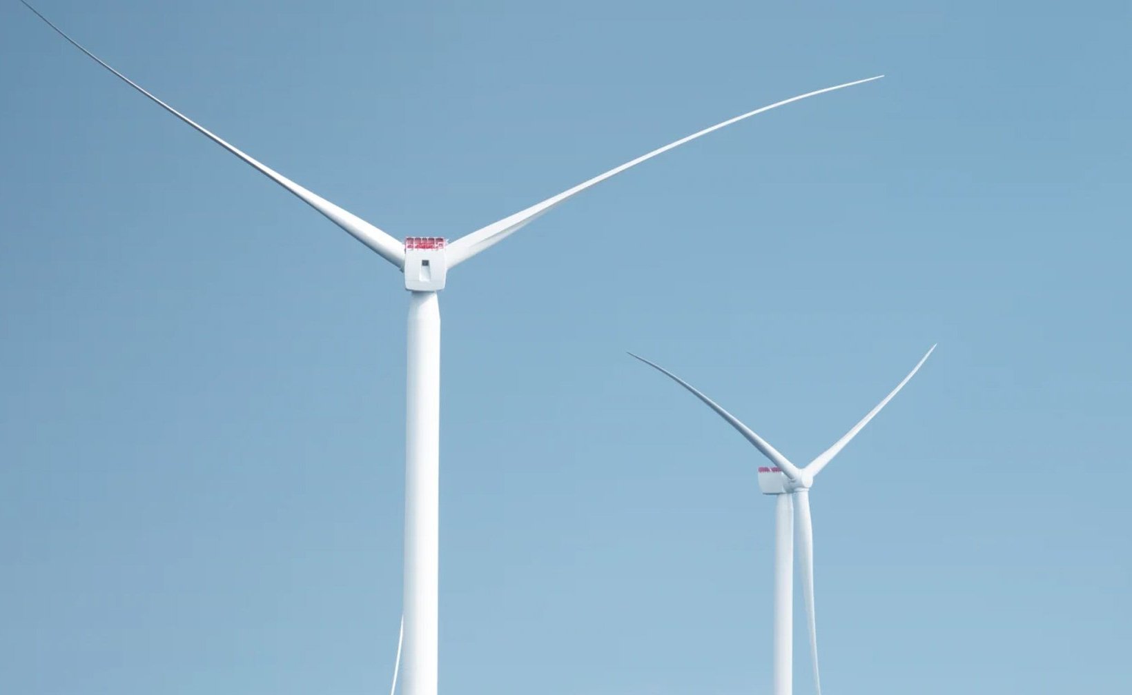 Two wind turbines against a clear blue sky.