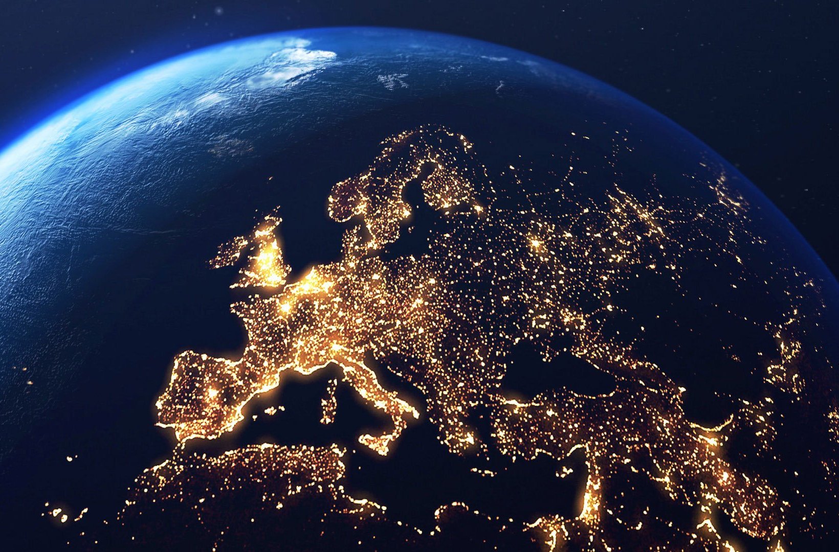 A view of Earth from space showing Europe at night, illuminated by thousands of city lights, with the curve of the planet visible against the dark sky.