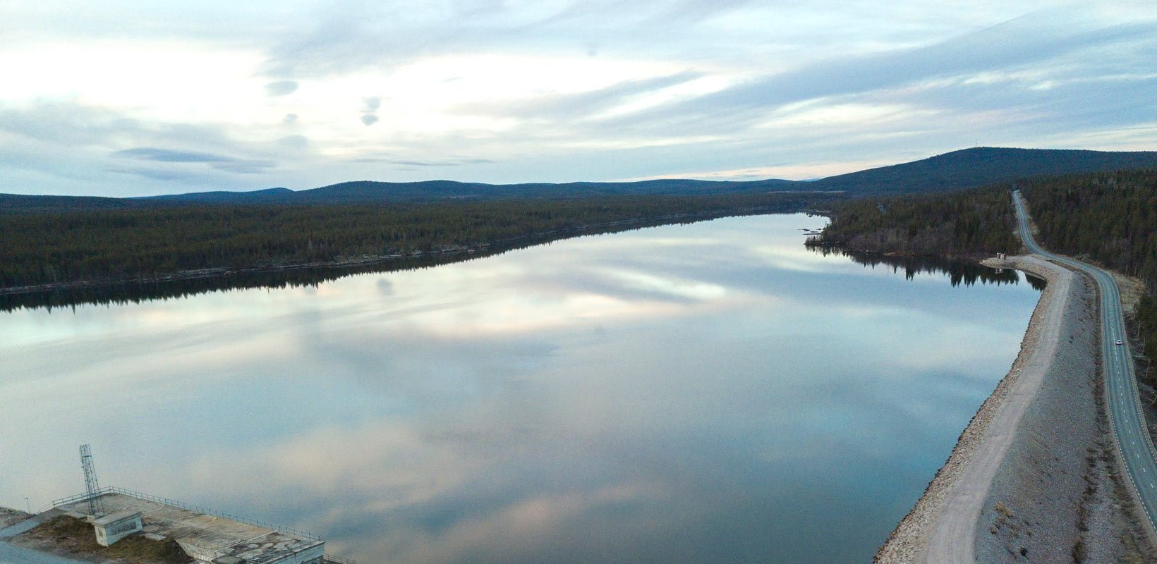 The reservoir at Harsprånget hydro power plant, bordered by forest, with a road running along the shoreline.