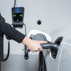 Woman connects e-mobile to charging station
