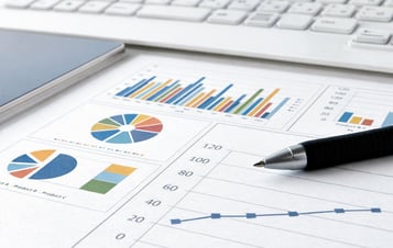 Printed financial charts on a desk, with a pen and a computer keyboard nearby. Printed financial charts on a desk, with a pen and a computer keyboard nearby.