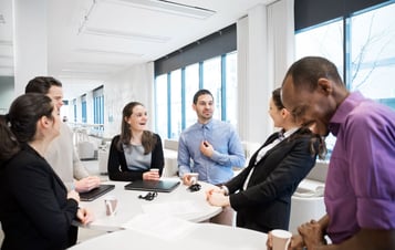 Colleagues standing at a table and laughing