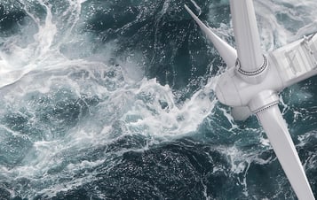 Close-up of a wind turbine above churning sea water.
