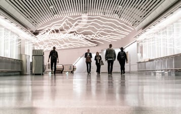 People walking through a wide indoor corridor with illuminated wall panels. People walking through a wide indoor corridor with illuminated wall panels.