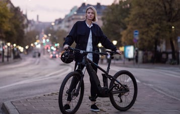 Woman with a bicycle standing on a street in Stockholm