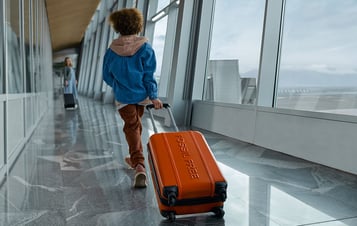 A boy drags a suitcase behind him in the airport
