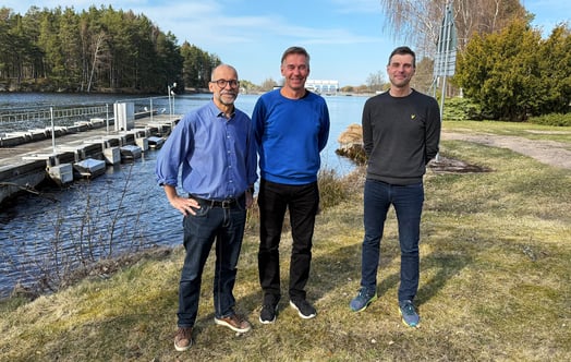 Erik Nordström, Per-Erik Thorsell and Bojan Stojanovic standing on a grassy bank beside a waterway, with trees, a dock and blue sky in the background. Erik Nordström, Per-Erik Thorsell and Bojan Stojanovic standing on a grassy bank beside a waterway, with trees, a dock and blue sky in the background.