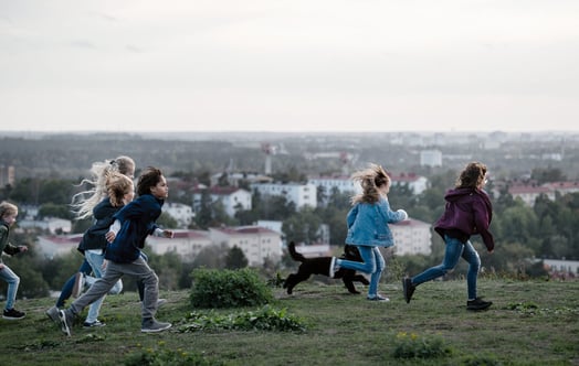 A group of children running across a hill
