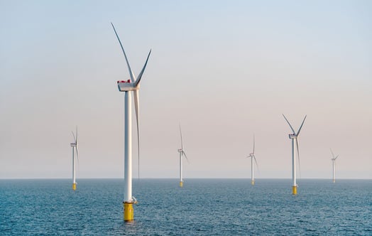 Six offshore wind turbines in a calm blue sea.
