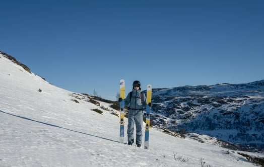 A skier holding a pair of skis made with parts from a wind turbine