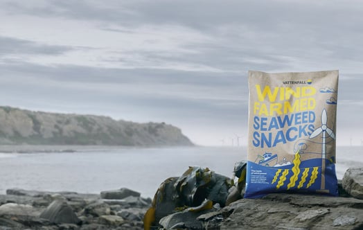 A bag of Vattenfall's seaweed snacks, with a wind farm in the background