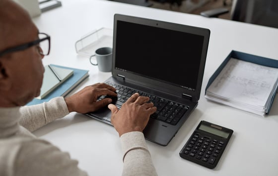 Close-up of a man typing on a laptop.