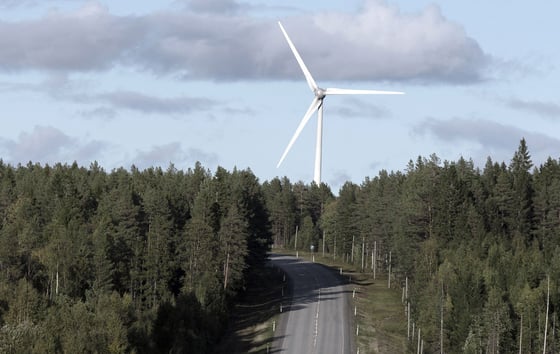 Wind turbine rising above a forest road in northern Sweden