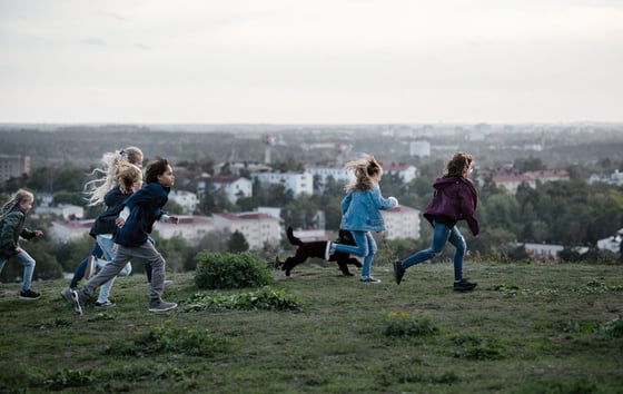 A group of children running across a hill A group of children running across a hill
