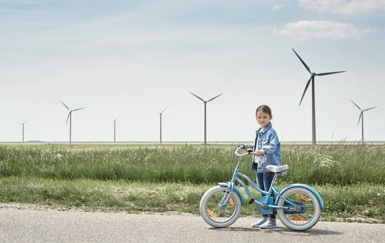 Girl with a bike in front of a wind farm