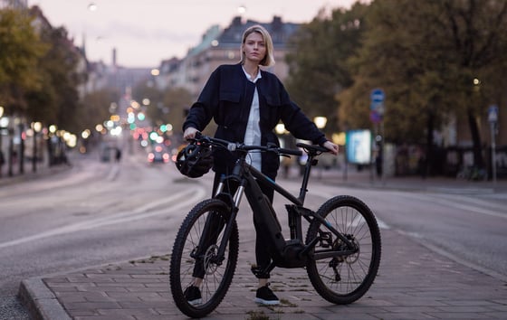 Young woman standing with her bicycle on a street in Stockholm