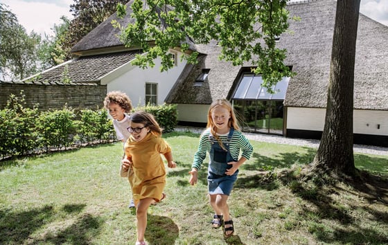 Three children running in a garden