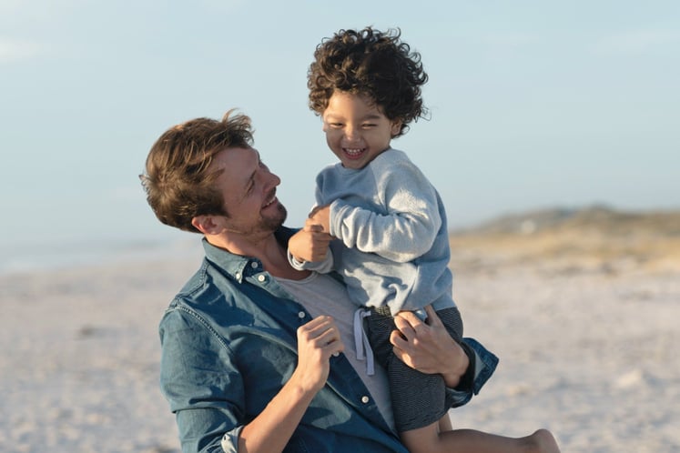A man with a young boy in his arms on a beach