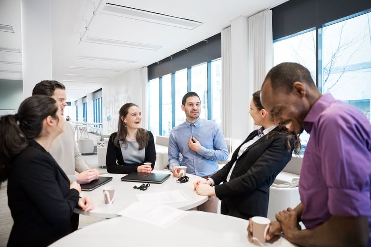 Staff standing around a table and laughing