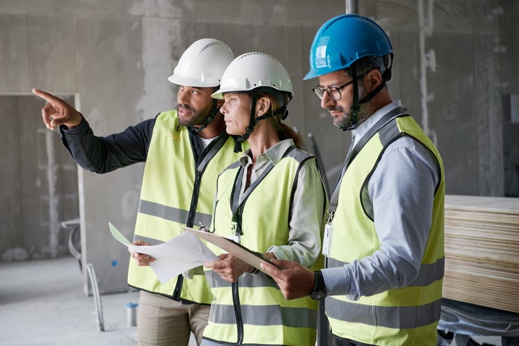 Three people in protective clothing on a construction site