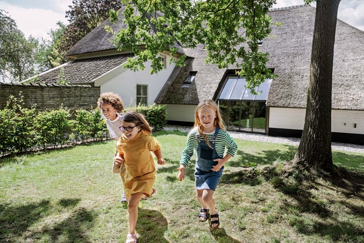 Three children running in a garden
