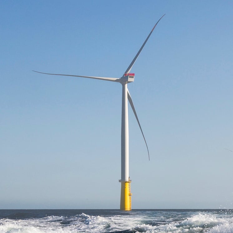 Offshore wind turbine, with waves in the foreground and a clear blue sky behind. Offshore wind turbine, with waves in the foreground and a clear blue sky behind.