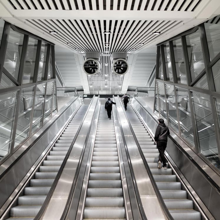 People going up escalators in a train station.