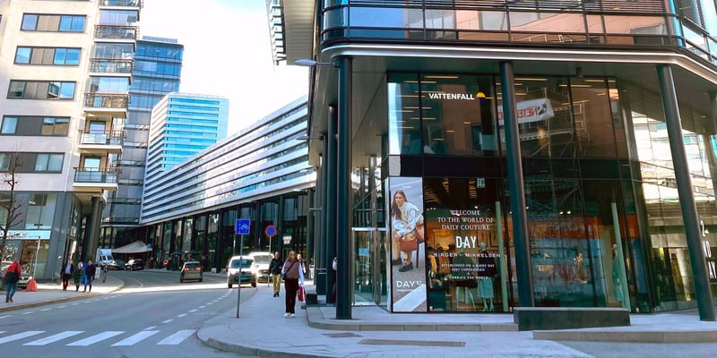 Glass-fronted Vattenfall office building on a street corner in Oslo, with high-rise buildings, pedestrians and cars. Glass-fronted Vattenfall office building on a street corner in Oslo, with high-rise buildings, pedestrians and cars.