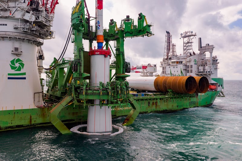 Specialized offshore vessel installing a monopile foundation in the sea for an offshore wind farm.