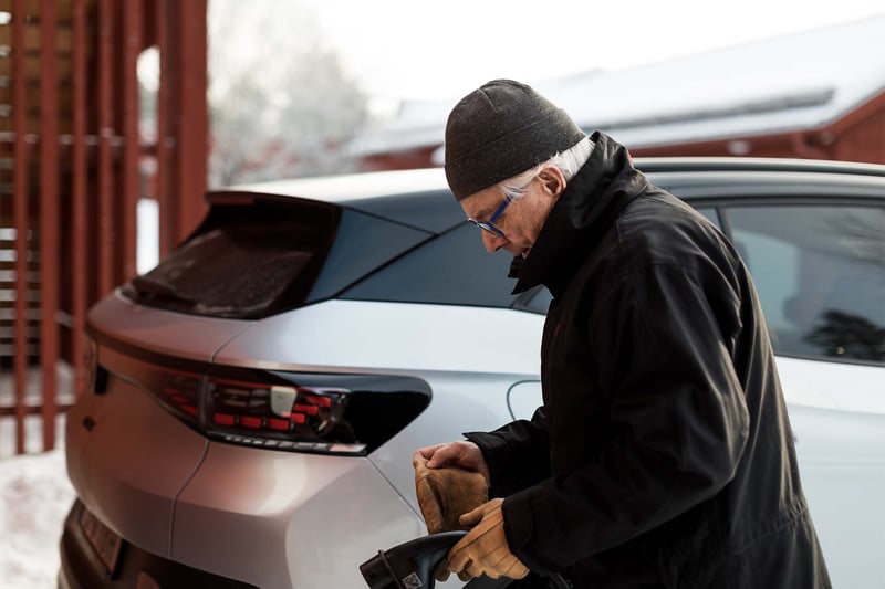 A man is standing in front of an electric car in a winter landscape. A man is standing in front of an electric car in a winter landscape.