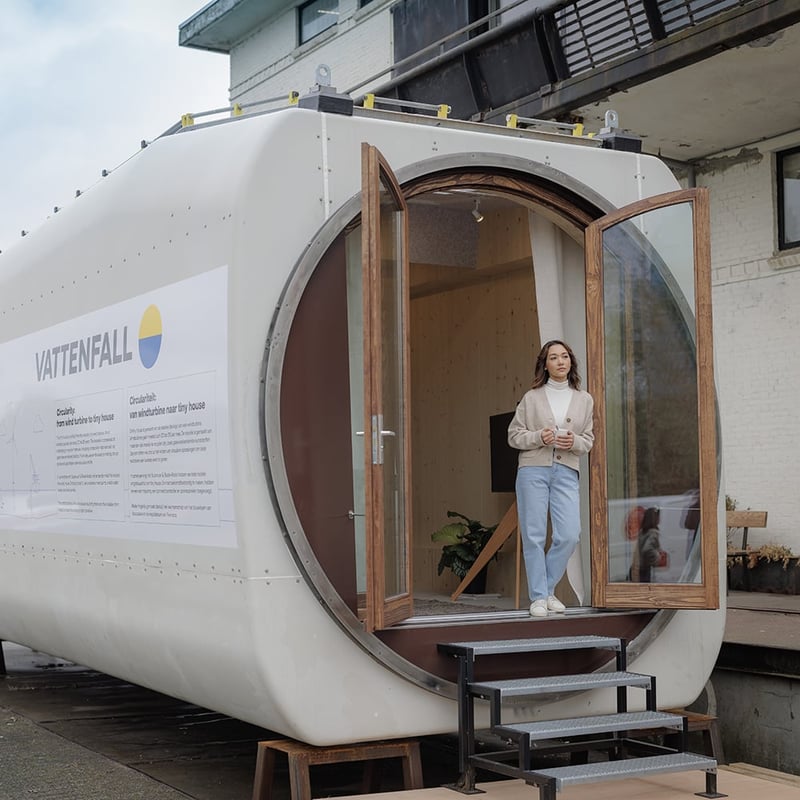 A woman is standing at the entrance to a tiny caravan.