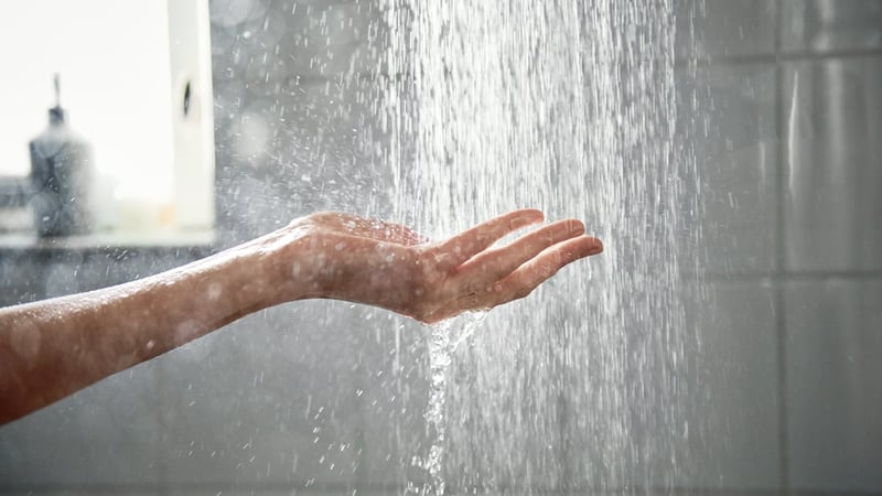 Woman holds hand under shower jet