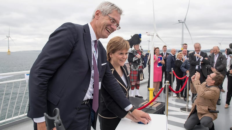 Magnus Hall and Nicola Sturgeon attending a ceremonial event on a vessel near offshore wind turbines.