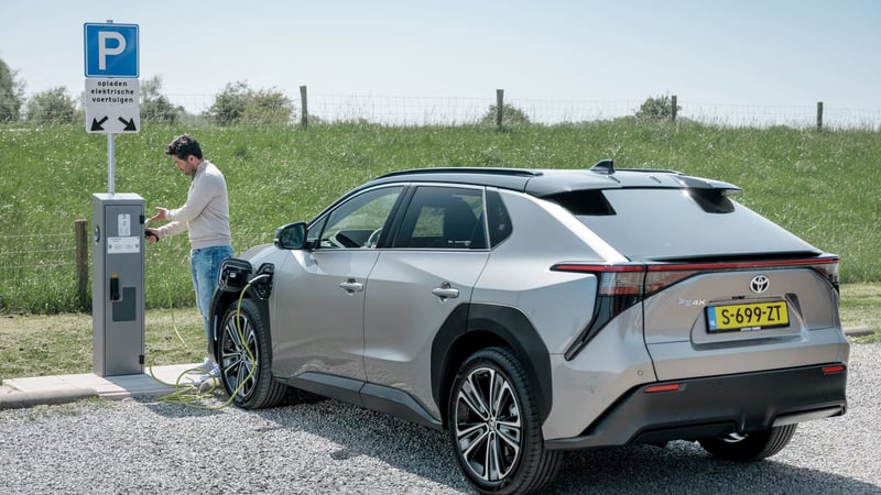 A man charging his electric car at an InCharge charging point on a sunny summer's day.