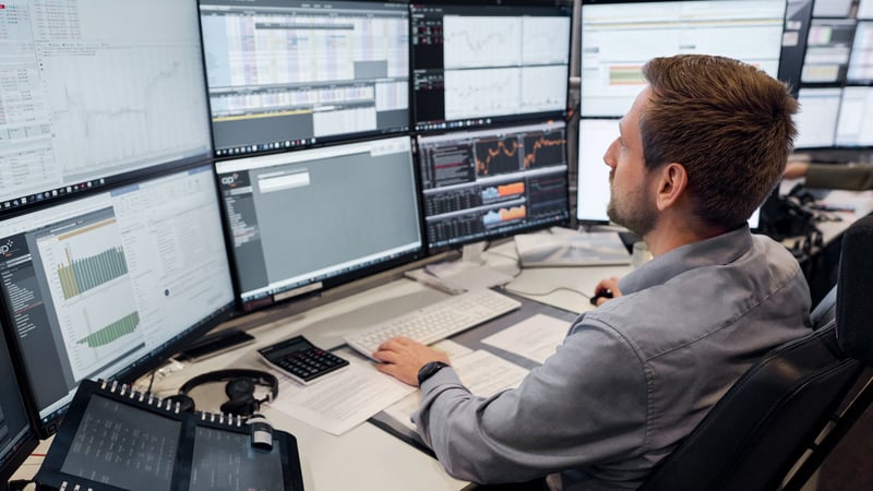 A man in front of several computer screens.
