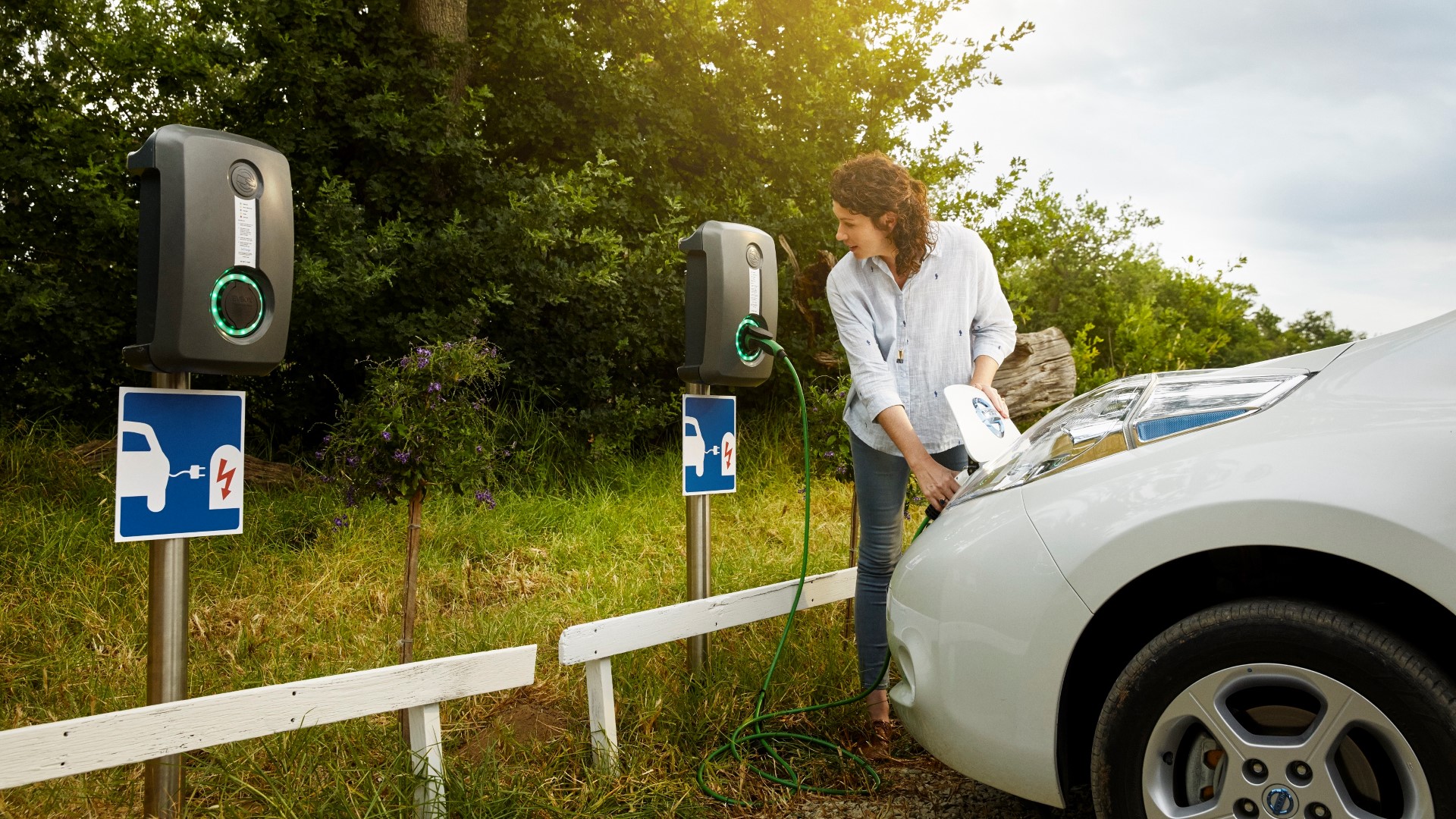 Woman using charging infrastructure to charge her electric vehicle