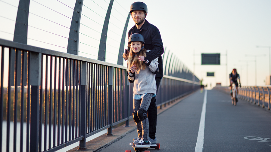 Vater mit Tochter auf einem e-Skateboard