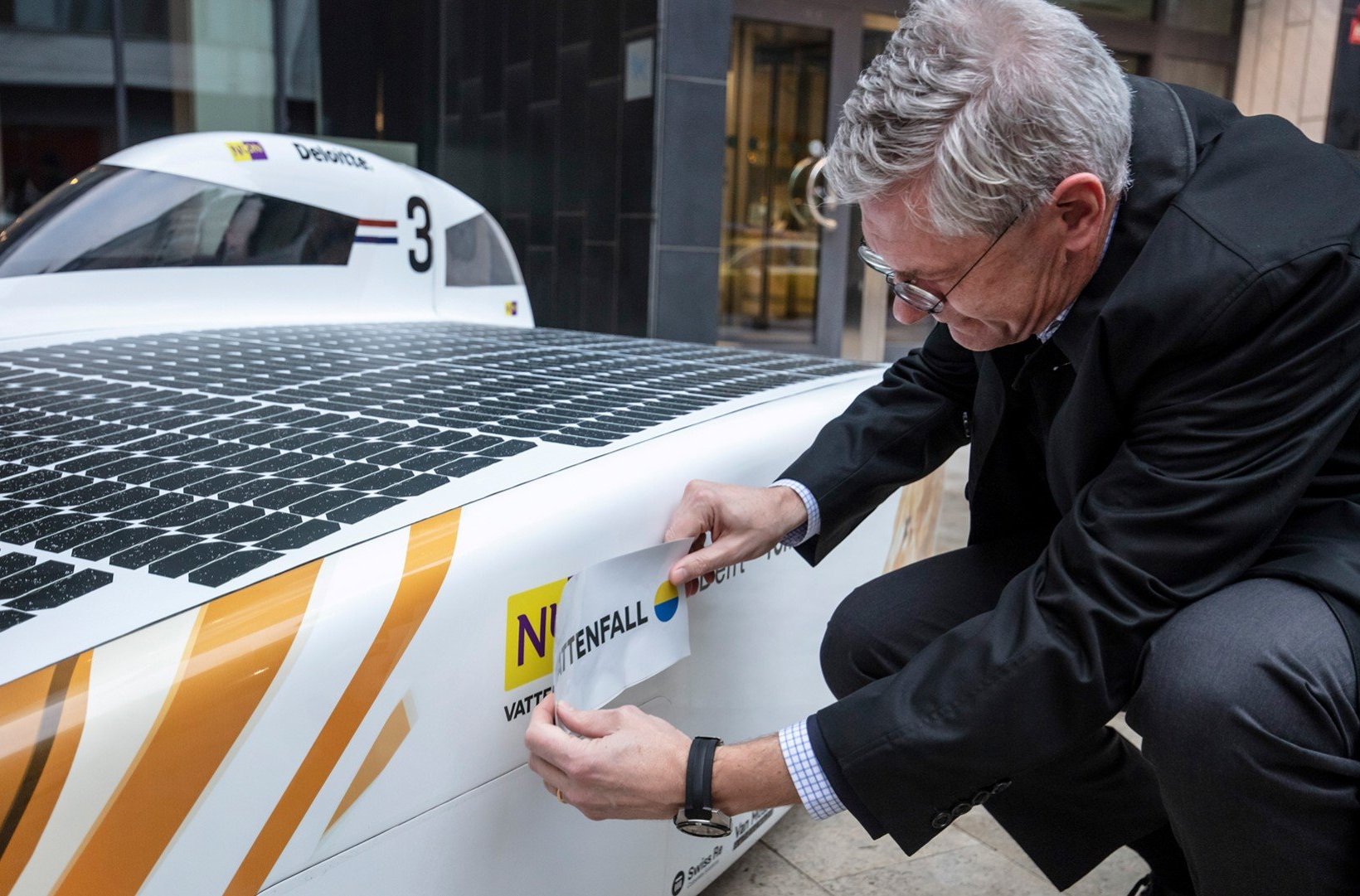 Magnus Hall klebt Vattenfall-Logo an das Nuon-Solarmobil