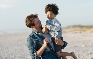 Ein Mann mit einem Kind im Arm am Strand