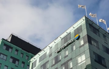 Die Zentrale von Vattenfall mit einer grünen Glasfassade, dem Firmenlogo und Flaggen auf dem Dach.