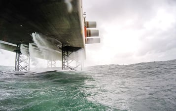 Wellen schlagen gegen das Fundament einer Anlage im Offshore-Windpark Sandbank.
