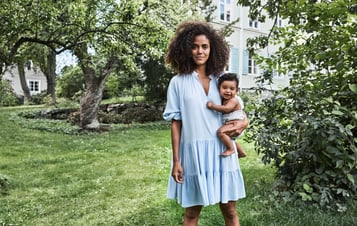 Frau mit Baby auf dem Arm im Garten stehend
