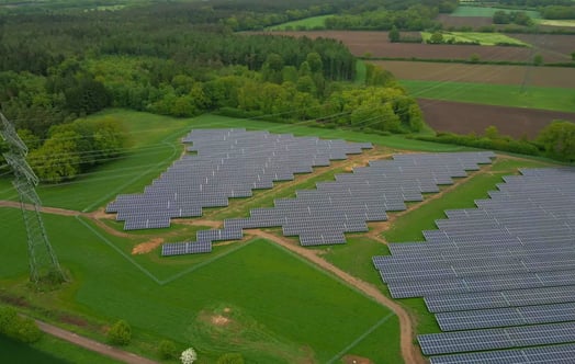 Luftbild des fast fertiggestellten Solarparks inmitten einer grünen Landschaft