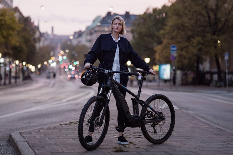 Frau steht neben ihrem Fahrrad auf einer Straße in Stockholm. Frau steht neben ihrem Fahrrad auf einer Straße in Stockholm.