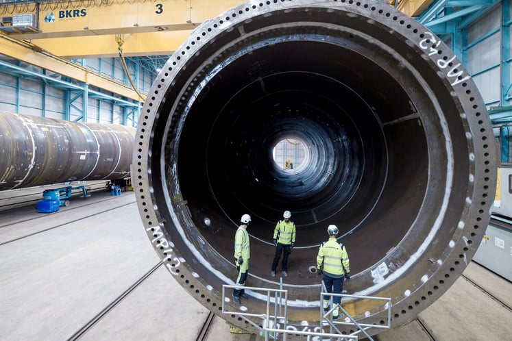 Drei Arbeiter bei der Inspektion eines Bauteils für eine Windkraftanlage