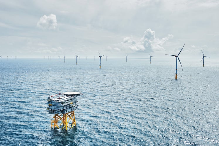 Luftaufnahme einer Offshore-Plattform und von Windkraftanlagen.