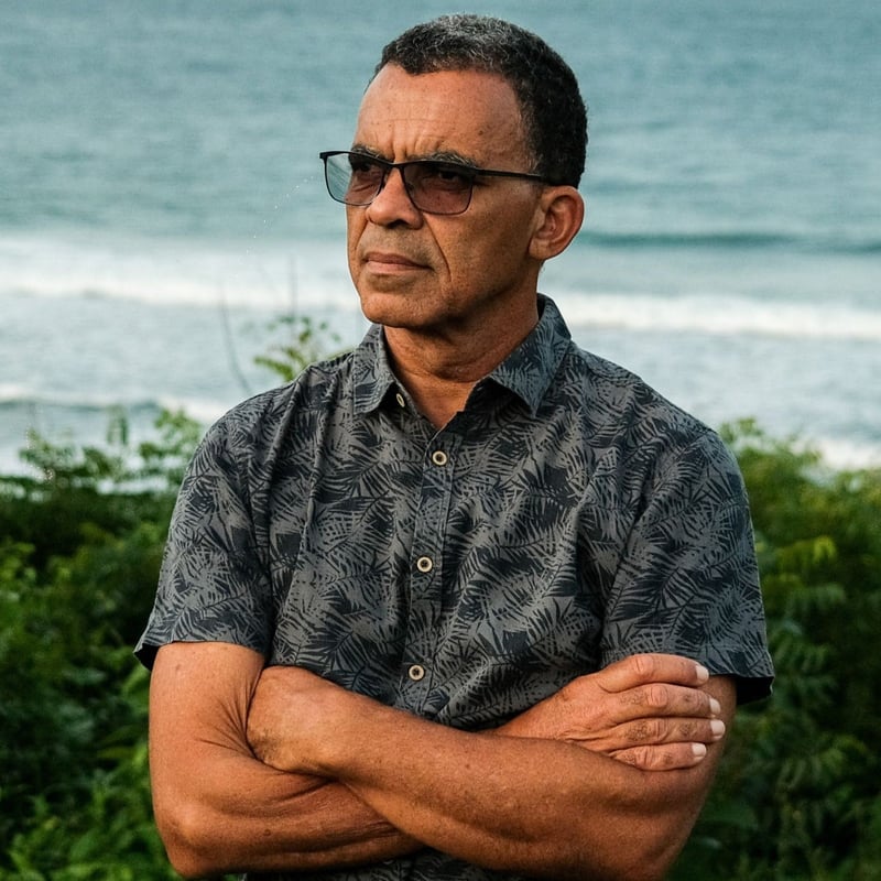 Dr. David Obura, der Vorsitzende der IPBES, steht mit verschränkten Armen am Ufer.