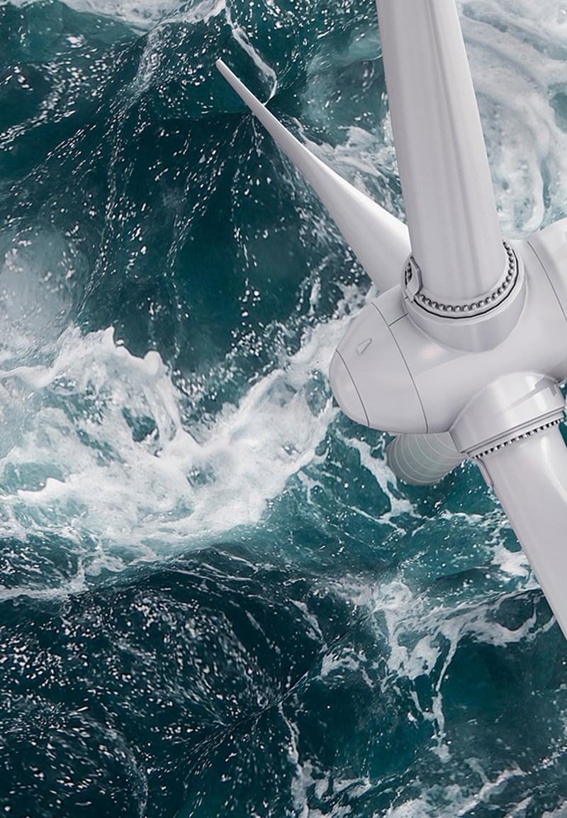Nahaufnahme einer Windkraftanlage über schäumendem Meerwasser.