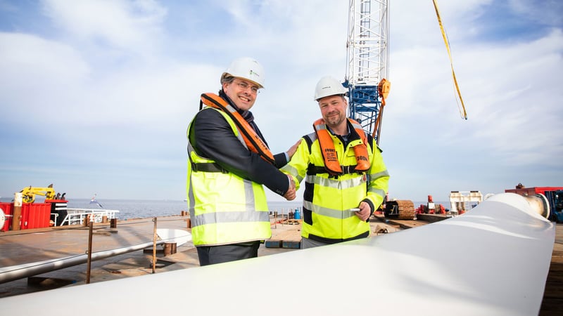 Robin van Buchem, Head of Operations NL bei Vattenfall, übergibt eines der Rotorblätter der Windkraftanlage an Philip Mol, President des MBO College Airport